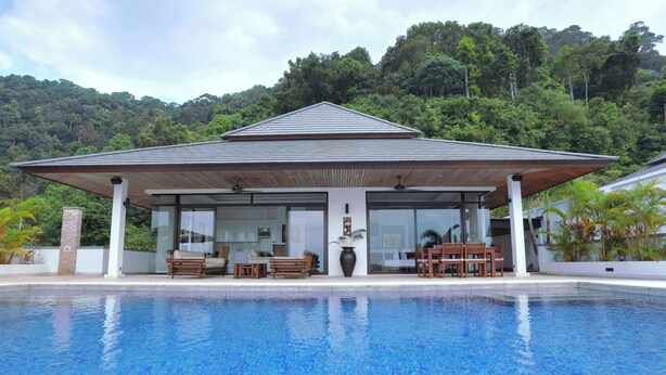 Une maison moderne avec une piscine, des meubles en bois et une vue sur une colline boisée.