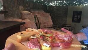 Ein Holzbrett mit verschiedenen Speisen, darunter Fleisch und Gemüse, das von zwei Personen getragen wird.