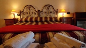 A neatly made bed with a red blanket, two bedside lamps, and rolled towels on the floor. - Agriturismo & Locanda Corte Marani (Badia Calavena)