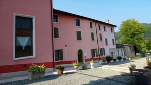 A pink building with multiple windows and a gravel courtyard. - Agriturismo & Locanda Corte Marani (Badia Calavena)