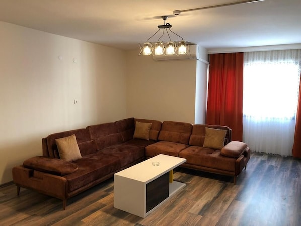 A living room with a brown sectional sofa, a white coffee table, and a ceiling light fixture.
