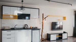 A modern kitchen with white cabinets, a built-in oven, and a flat-screen TV.