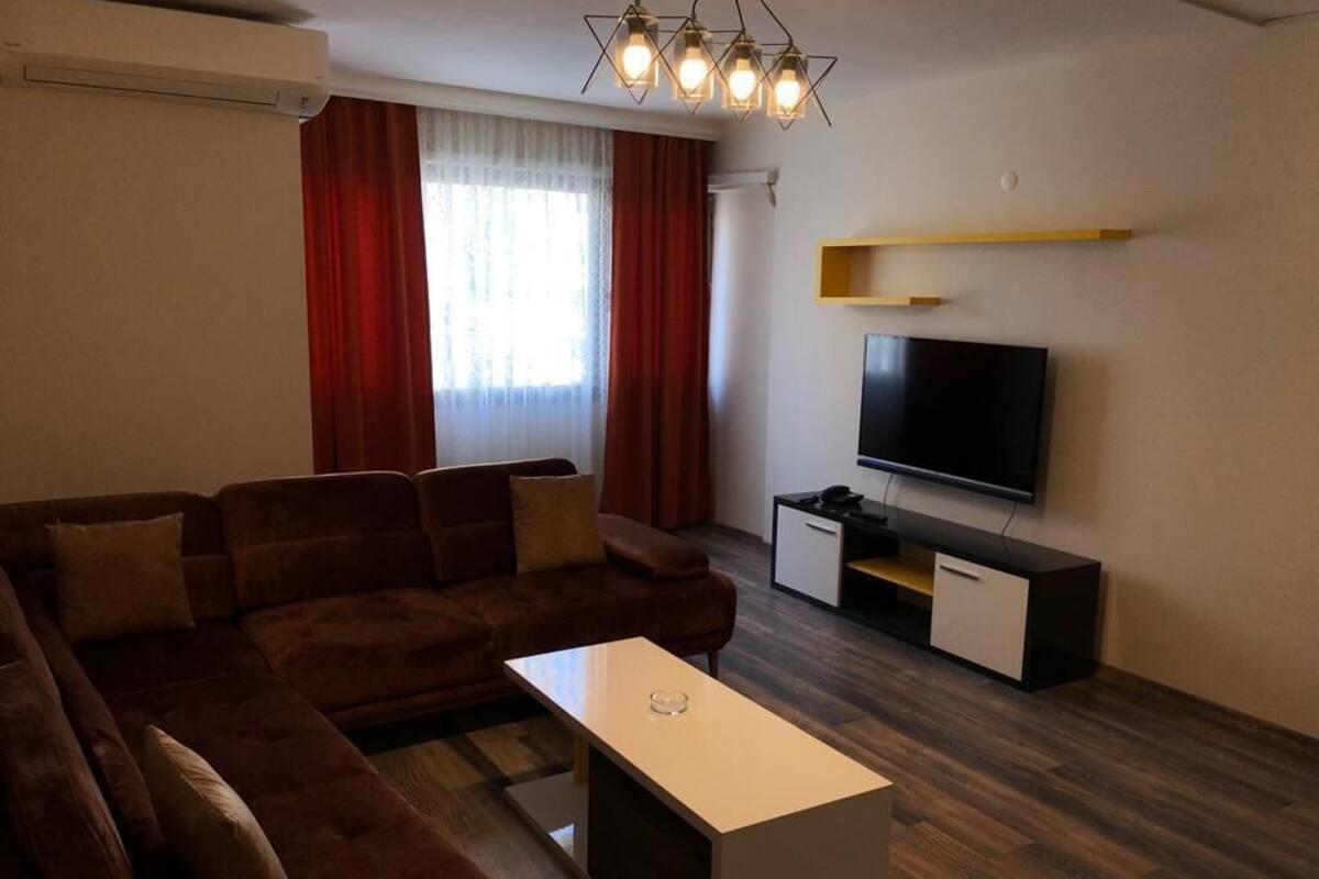 A modern living room with a sectional sofa, a flat-screen TV, and a minimalist coffee table.