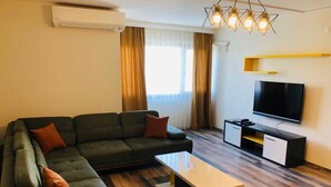A modern living room with a sectional sofa, a coffee table, a flat-screen TV, and a built-in entertainment unit.