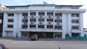 Um edifício com várias andares, fachada simétrica, janelas amplas e aparelhos de ar condicionado.