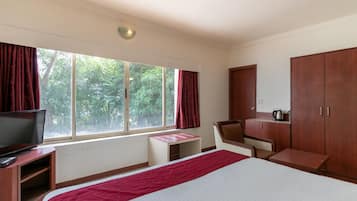 A hotel room with a bed, a desk, a chair, a television, and a wardrobe.