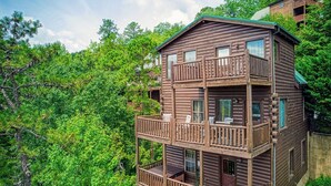 A multi-story log cabin with balconies, surrounded by dense forest. - All About The View, Spacious Mountain Getaway, Perfect for Families & Groups (Sevierville)