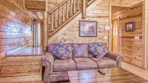 A wooden interior with a sofa, a staircase, and framed pictures on the walls. - All About The View, Spacious Mountain Getaway, Perfect for Families & Groups (Sevierville)