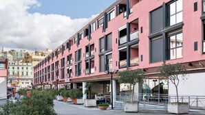 Un edificio de varios pisos con balcones, plantas en macetas y cielo despejado.
