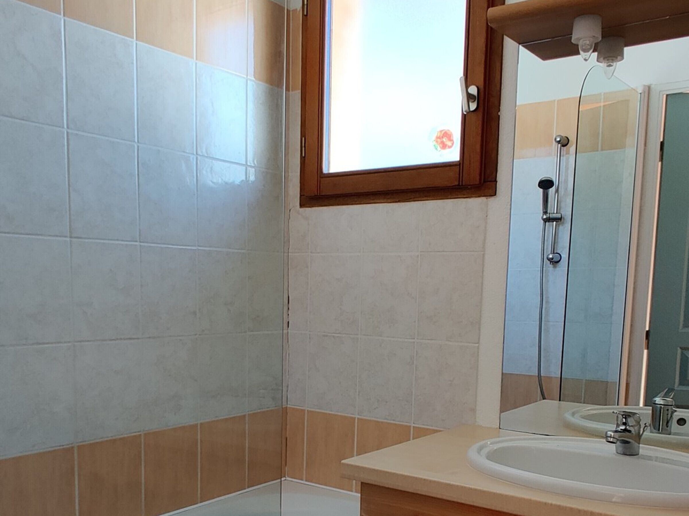 A bathroom with a shower, a sink, and a window.