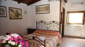 A bedroom with a bed, a nightstand, a lamp, a window, and a radiator. - Bungalow with Garden View (Palestrina)