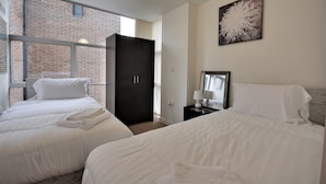 Une chambre d’hôtel avec deux lits, une armoire sombre, une grande fenêtre et une œuvre d’art accrochée au mur.