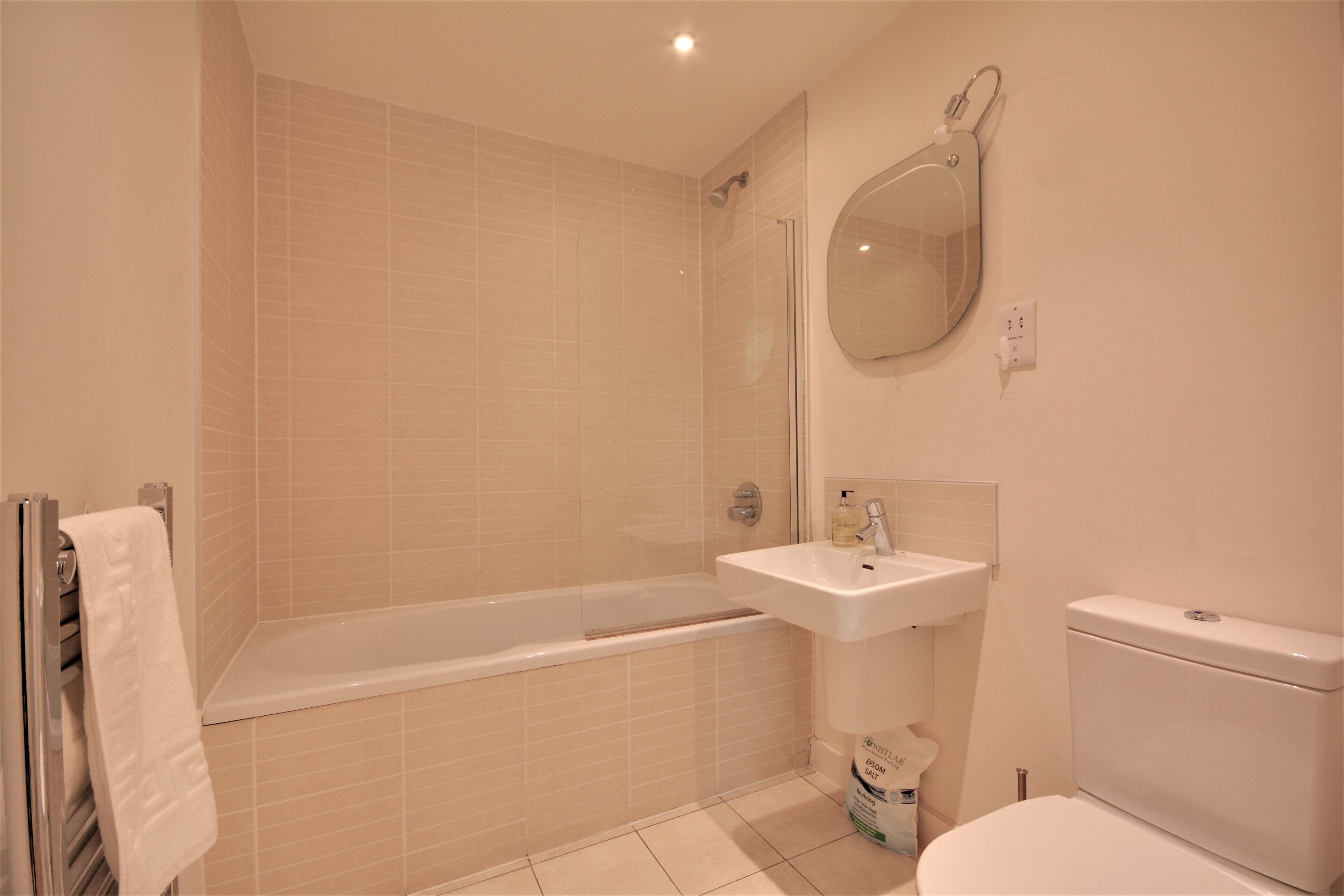 A bathroom with a bathtub, sink, toilet, and a mirror.