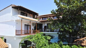 A two-story building with a balcony, white walls, and a tiled roof. - Sofia Studios (Skiathos)