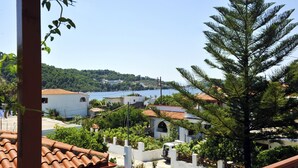 A coastal town with terracotta-roofed buildings, lush greenery, and a clear view of the sea. - Sofia Studios (Skiathos)