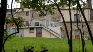 Ein zweistöckiges Steinhaus mit einer Steintreppe, die zu einem Balkon führt.