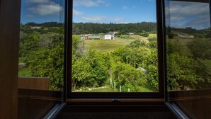 Ein Zimmer mit großem Fenster und Blick auf eine ländliche Landschaft mit Häusern und Grünflächen.