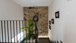 Eine Treppe mit einer Steinwand, einer Uhr und gerahmten Bildern.