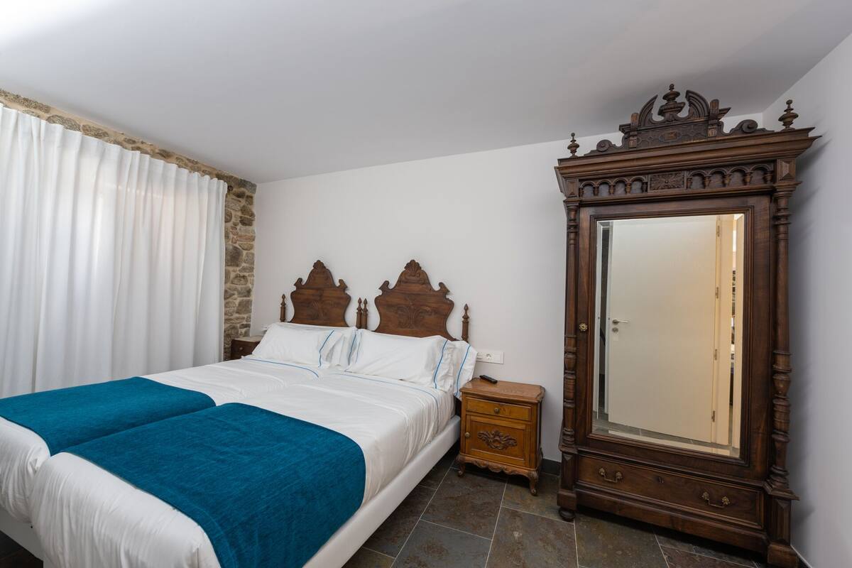 Quarto com cama, mesa de cabeceira, cômoda e um espelho grande.