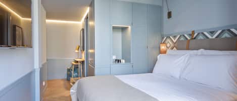 A modern hotel room with a bed, a wardrobe, a mirror, and a bedside table.