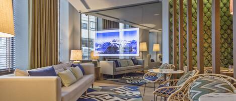 A modern living room with a sofa, chairs, a TV, and a patterned rug.