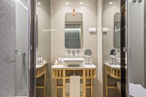 Un baño moderno con cabina de ducha de vidrio, tocador con lavabo y espejo.