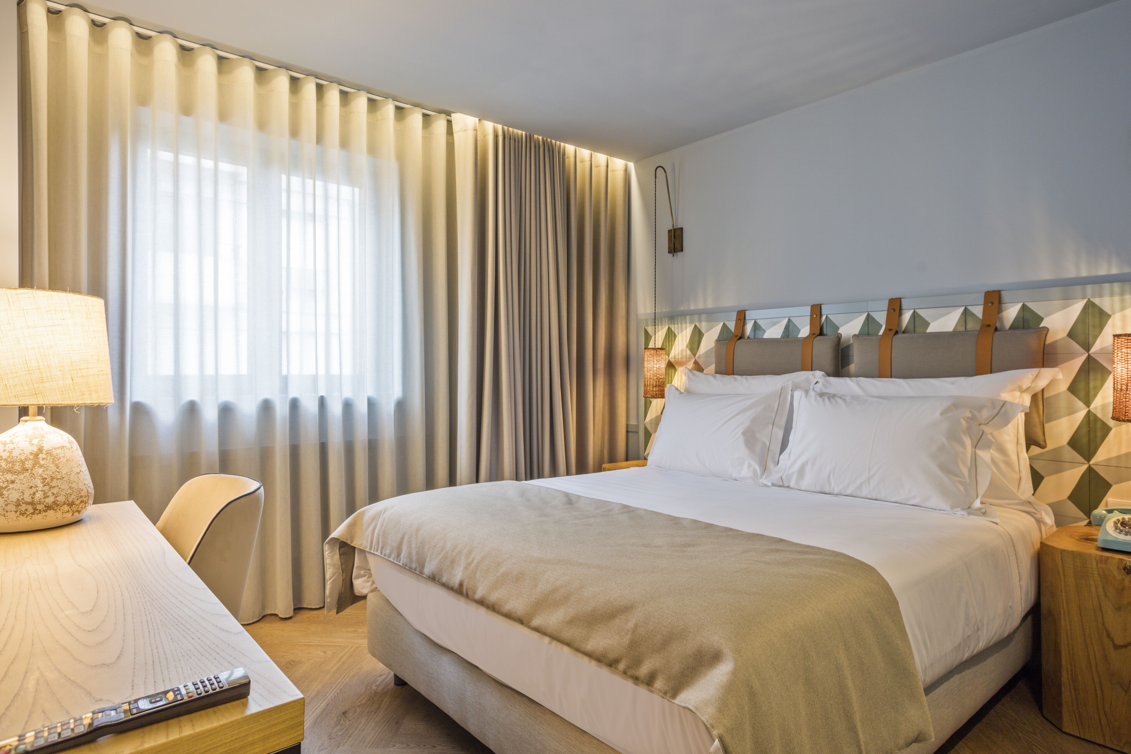 Une chambre d’hôtel comprenant un lit, une table de chevet avec une lampe, une chaise et une petite table de nuit avec un téléphone.