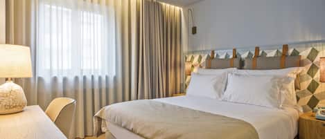 Une chambre d’hôtel comprenant un lit, une table de chevet avec une lampe, une chaise et une petite table de nuit avec un téléphone.