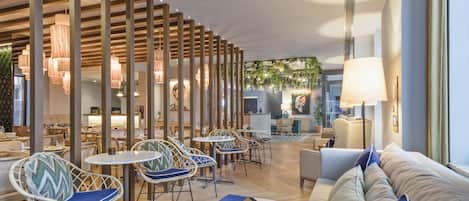 Een moderne hotel lobby met een centraal zitgedeelte, een bank en een receptiebalie.