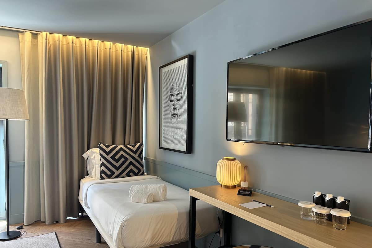 Een hotelkamer met een bed, een bureau, een televisie en een raam met gordijnen.
