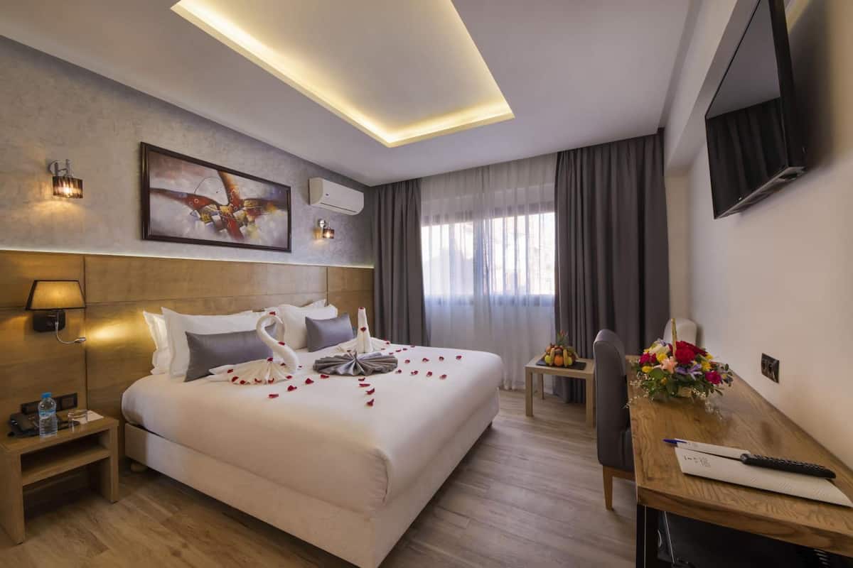 Ein Hotelzimmer mit einem großen Bett, einem Nachttisch und einem Schreibtisch mit Stuhl.