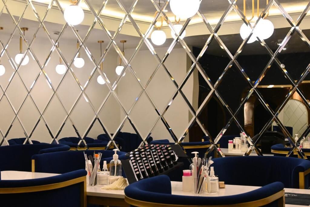 Une chambre d’hôtel dotée d’un mur miroir, d’un minibar et d’un coin salon avec tables et chaises.