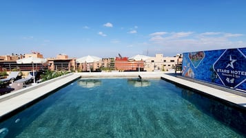 Una piscina techada, una piscina al aire libre, sombrillas