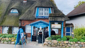 A traditional thatched-roof building with a blue sign reading "Oma's Kaffeestuev". - Apartment with loggia in a quiet complex, about 10 minutes walk to the (Holm)