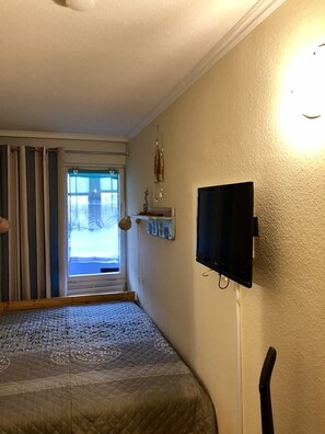 A bedroom with a bed, a television mounted on the wall, and a window with curtains. - Apartment with loggia in a quiet complex, about 10 minutes walk to the (Holm)