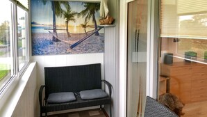 A room with a beach-themed mural, a wicker sofa, and a sliding door leading to a balcony. - Apartment with loggia in a quiet complex, about 10 minutes walk to the (Holm)
