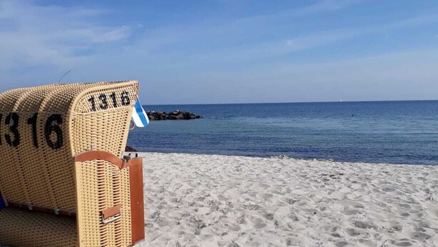 A beach with a wicker chair labeled "1316" and a rocky outcrop in the water. - Apartment with loggia in a quiet complex, about 10 minutes walk to the (Holm)