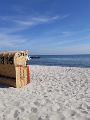 A beach with a wicker chair labeled "1316" and a rocky outcrop in the water. - Apartment with loggia in a quiet complex, about 10 minutes walk to the (Holm)