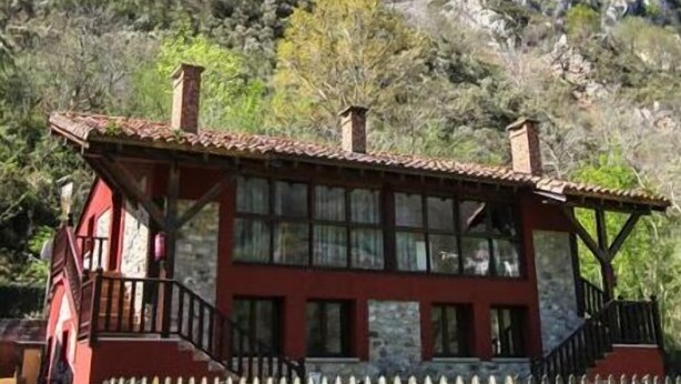Un bâtiment rouge, surmonté d’une clôture en bois, se dressant sur un fond de montagnes.