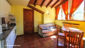 Une cuisine compacte avec un coin repas, un plafond en bois et une fenêtre avec des rideaux.