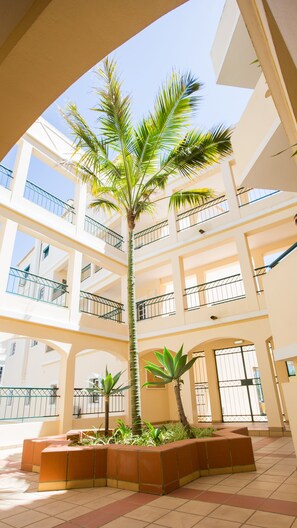 A multi-level atrium with a central palm tree surrounded by planters. - Apartamentos Quinta da Praia (Portimão)