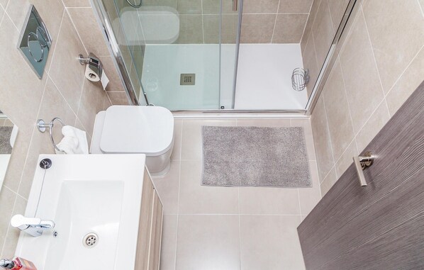 Ein modernes Badezimmer mit Duschkabine aus Glas, einer weißen Toilette und einem Waschbecken mit Handtuchhalter.
