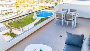 A balcony with a pool view, outdoor seating, and a modern design.