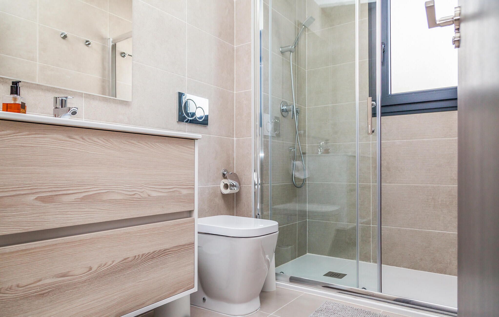 Une salle de bain moderne comprenant des toilettes, un espace douche et un meuble-lavabo avec un miroir.