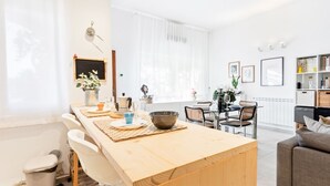 A modern kitchen with a wooden island, white cabinetry, and a dining area with chairs and a table. - GuestHost - Large and bright 90sqm open space, with independent entrance, garden and private parking, located on the ground floor of a villa in the north area of Catania, just 15 minutes by car from the historic center.The apartment is equipped with all  (Catania)