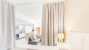 A hotel room with a bed, a sofa, a lamp, and a view of the kitchen and living area. - GuestHost - Large and bright 90sqm open space, with independent entrance, garden and private parking, located on the ground floor of a villa in the north area of Catania, just 15 minutes by car from the historic center.The apartment is equipped with all  (Catania)