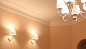 Un coin repas avec des meubles blancs, deux lampes fixées au mur et des plantes en pot.