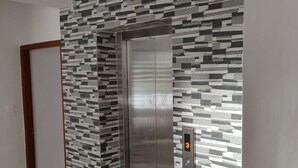 A modern elevator with a metallic finish, surrounded by a wall with a geometric pattern. - Thulasi Inn (Kanayannur)