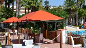 Un espace aménagé au bord de la piscine, avec des chaises longues, des parasols et une piscine.