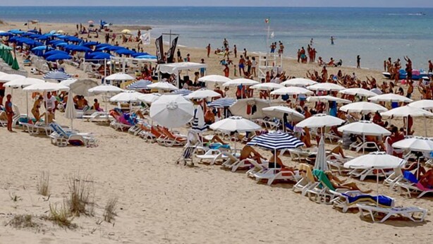 Une plage bondée, avec de nombreux parasols et des chaises longues.